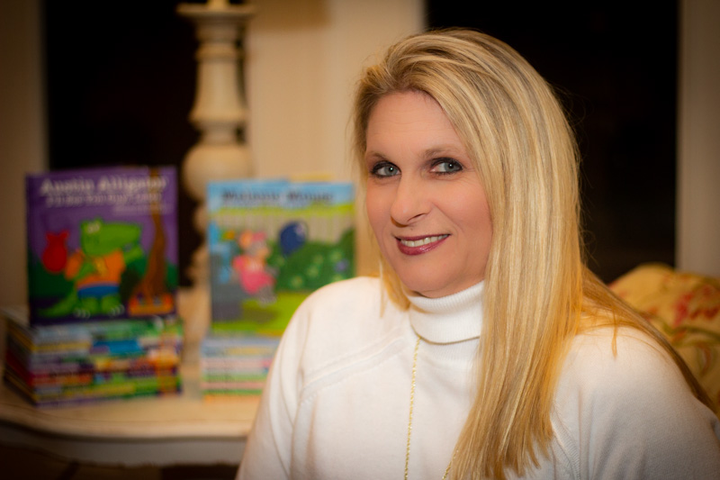 Closeup of author Cindy Foust seated with her books stacked in the background